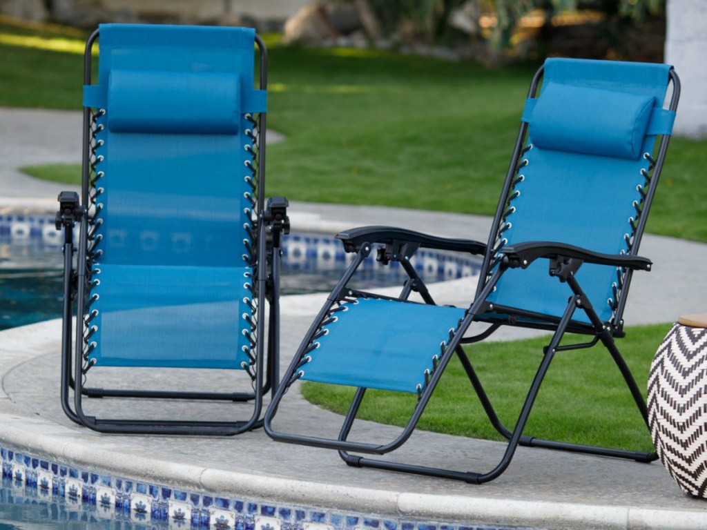 two blue recliner chairs sitting outside by pool