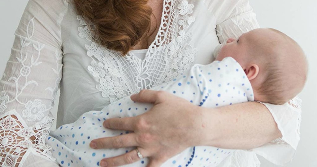 woman holding baby in a swaddling blanket