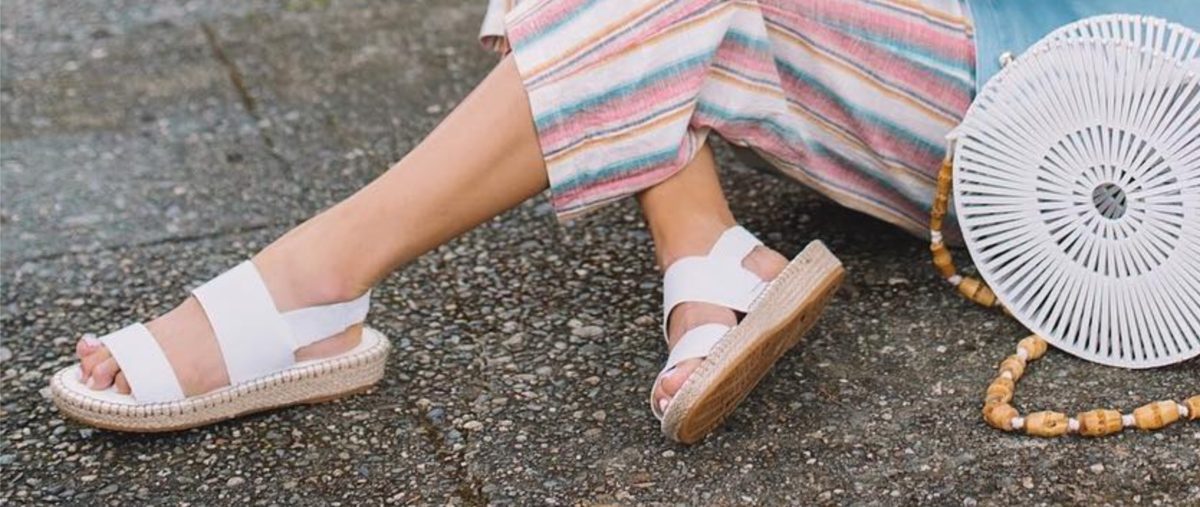 woman in white espadrille sandals sitting on ground outside