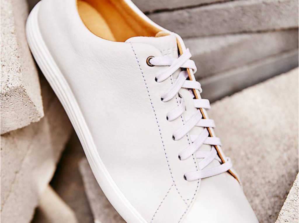 white casual sneakers standing against concrete blocks