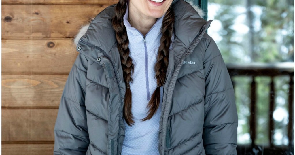 woman standing in front of a cabin wearing a coat