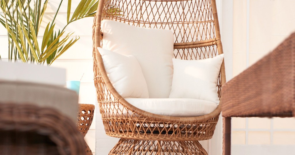 wicker egg chaped chair with white cushions in an outdoor patio space