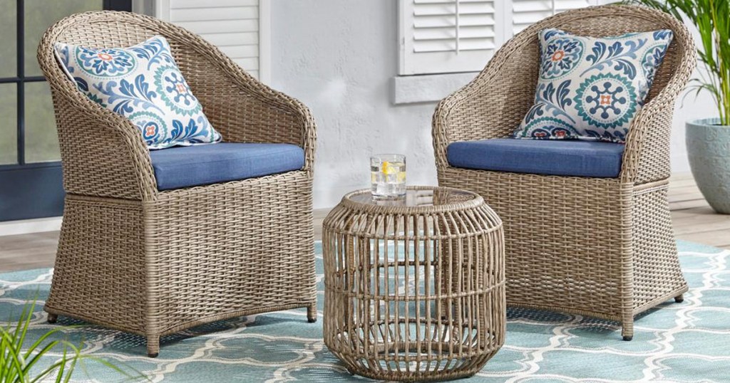 two picker patio chairs with blue cushions and matching wicker patio table