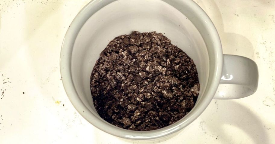 chocolate cookies mashed up in a mug on the counter in order to make cake