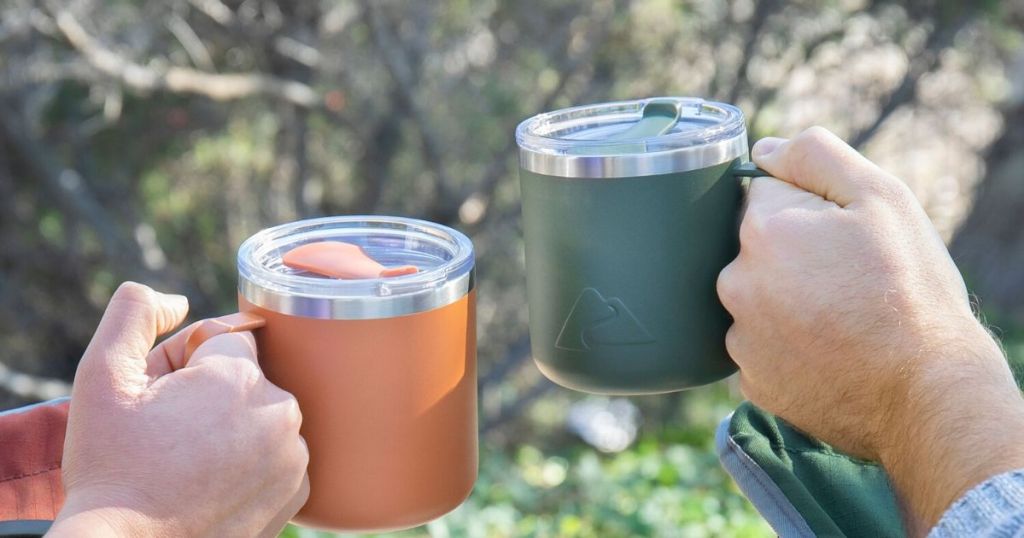 two hands each holding an insulated stainless steel mug