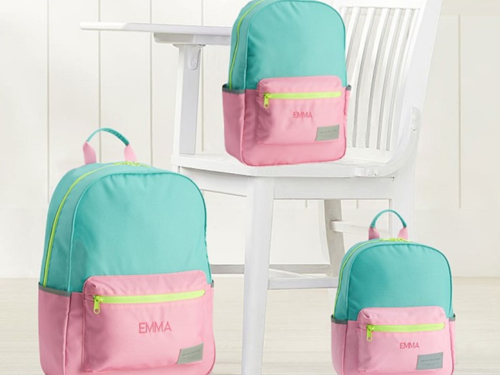 3 potter barn kids backpacks sitting next to each other by a white chair