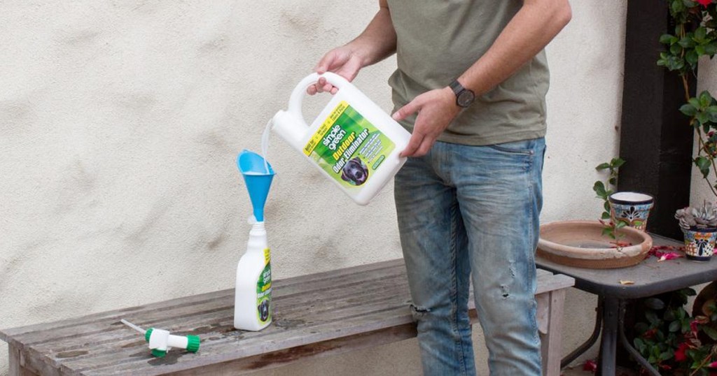 person refilling small bottle of simple green with larger refill bottle on garden bench