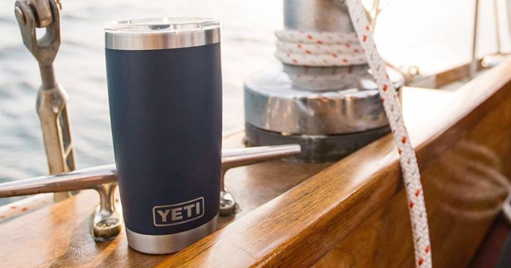 navy blue yeti brand tumbler sitting on wooden edge of sailboat