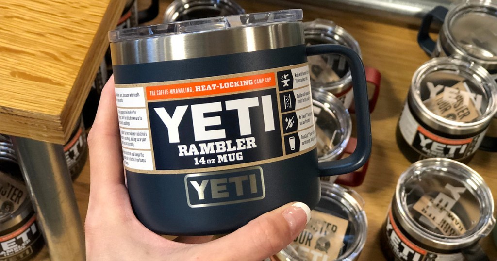 person holding up a black yeti brand coffee mug