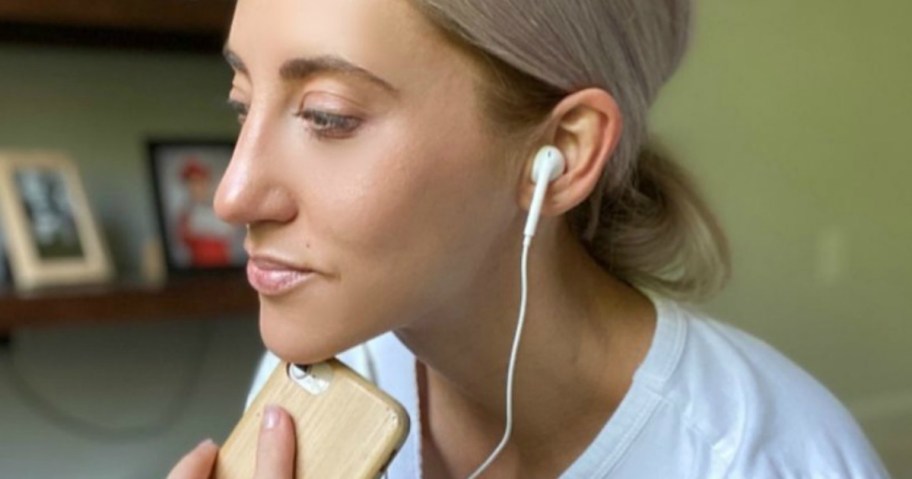 woman wearing headphones and a phone by bookcase