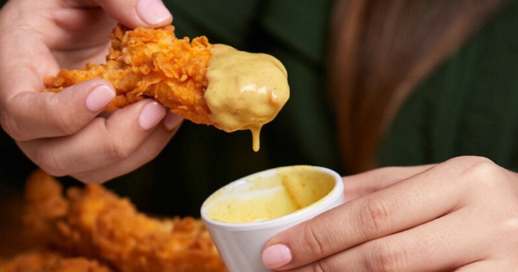 dipping chicken strip in honey mustard