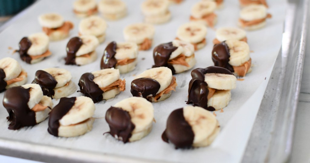 chocolate dipped peanut butter banana bites on a sheet pan