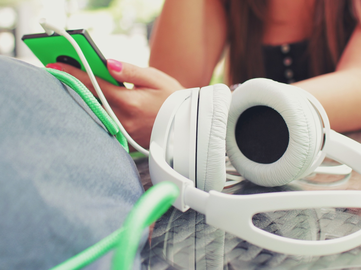 girl holding phone with earphones on table