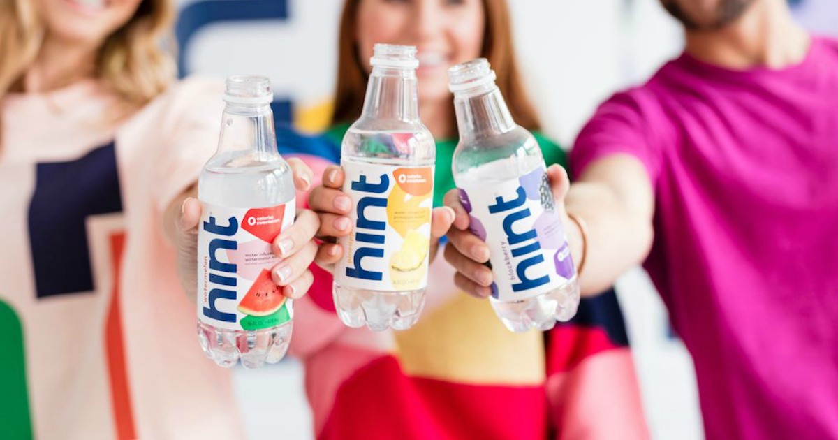 three people holding up hint water bottles