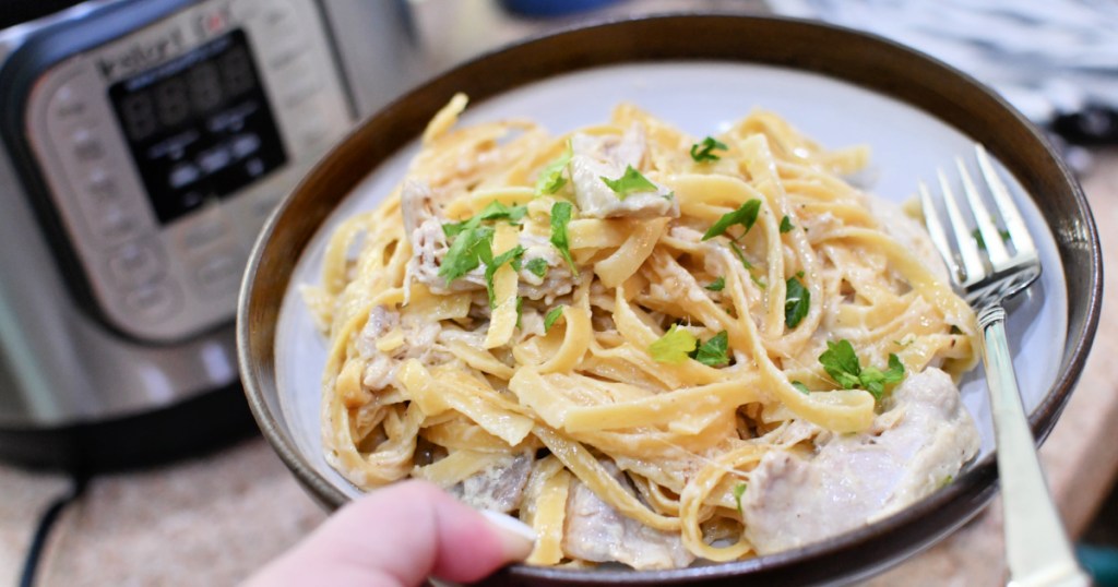 holding a plate of fettuccine alfredo