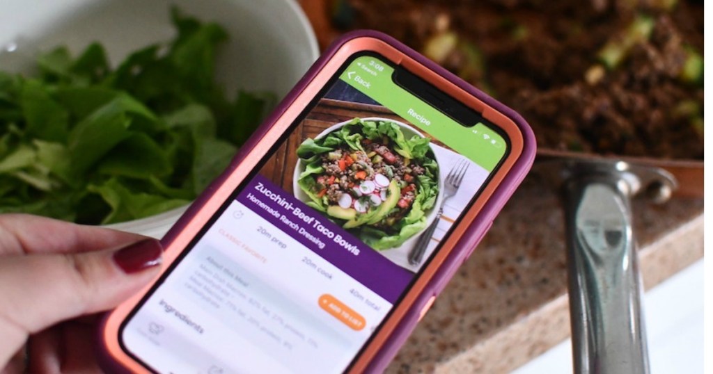 holding iphone with eMeals recipe on screen