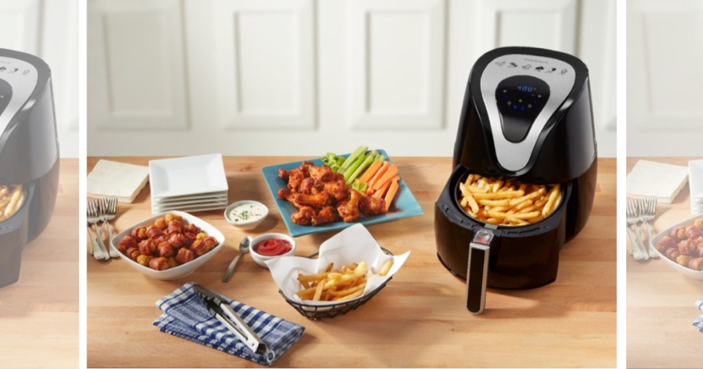 digital air fryer with basket opened filled with fries on table with fried foods nearby