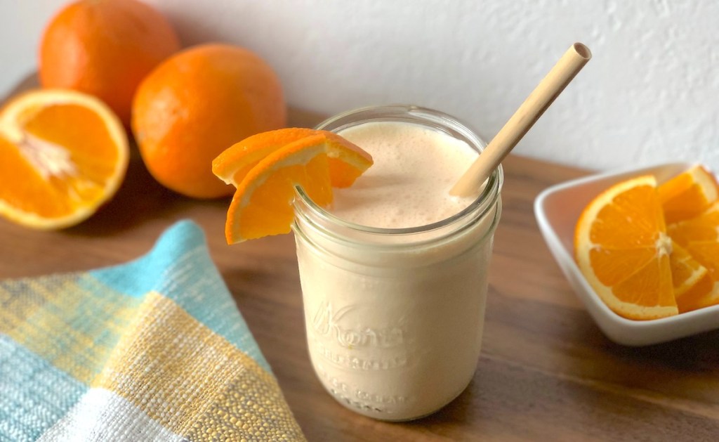 orange colored smoothie with sliced and whole oranges in the background