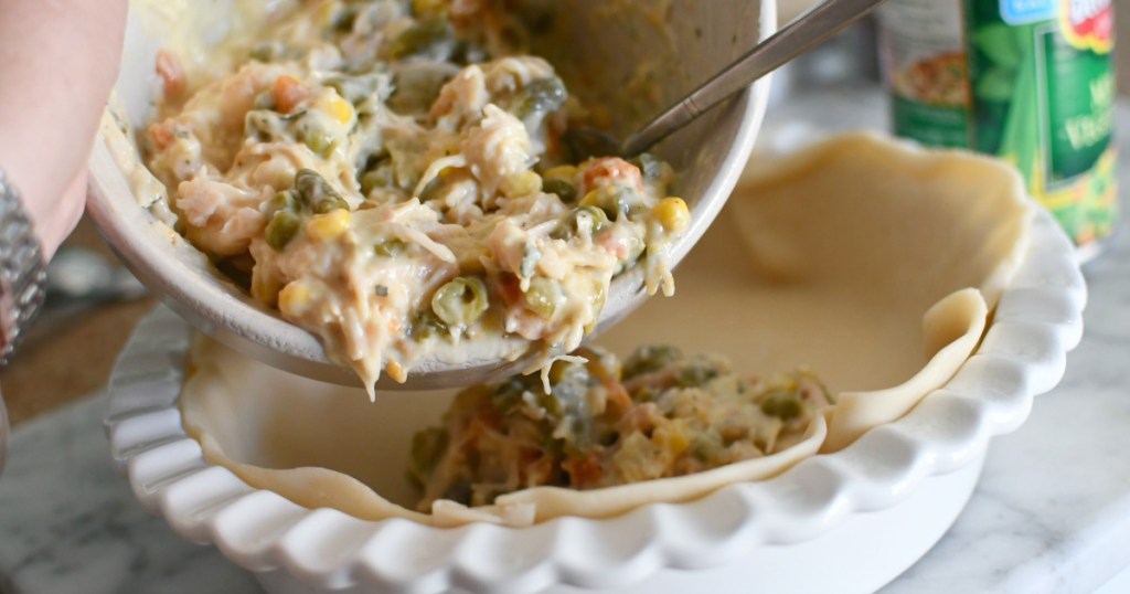 pouring chicken pot pie filling in a pie pan