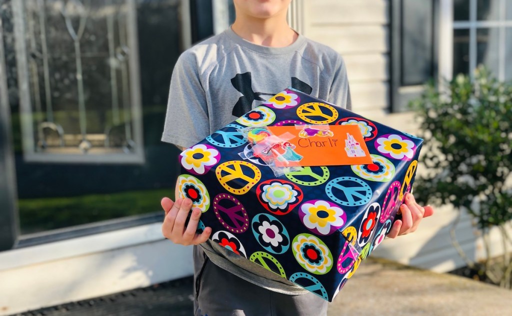 boy holding birthday present outside with peace signs and flowers