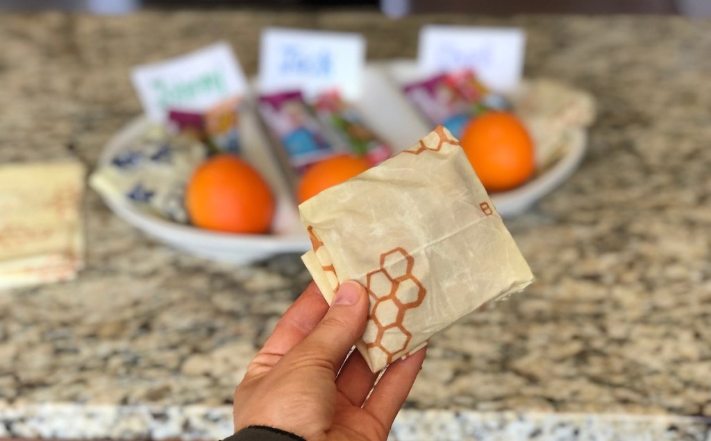 hand holding a bees food wrap with snack tray in background