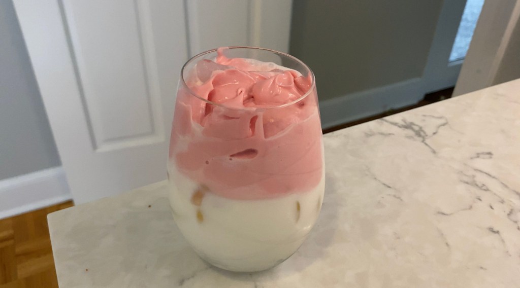 glass sitting on countertop with fluffy whipped cream beverage