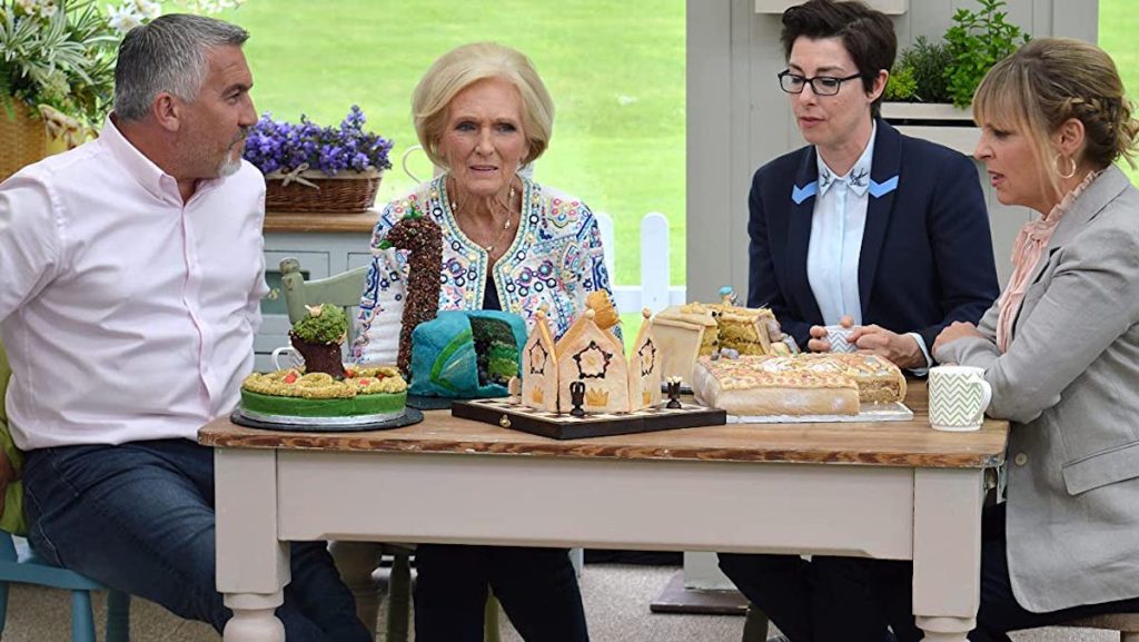 man and three woman sitting around a table with gingerbread house 