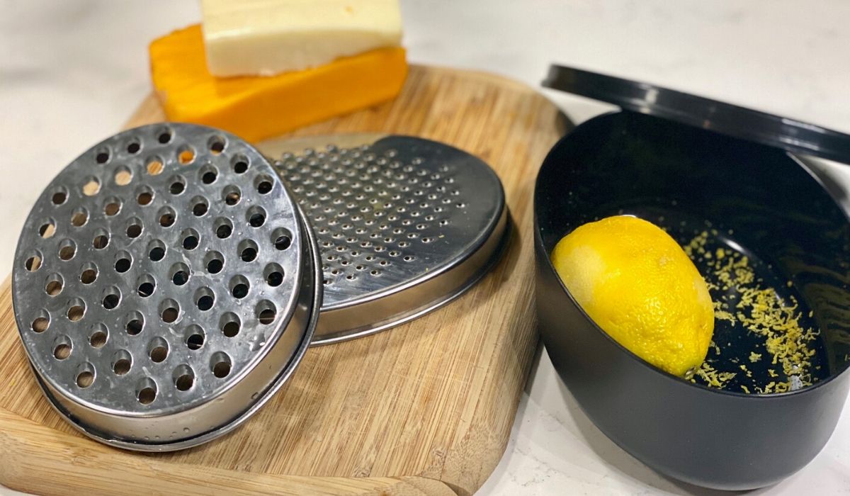 Amazon cheese grater and citrus zester with storage onlinepartment sitting on the counter with a lemon and block cheese