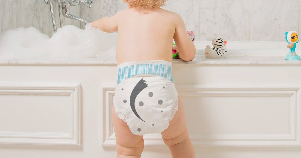 baby laying on pink blanket wearing diaper with fox tail printed on back