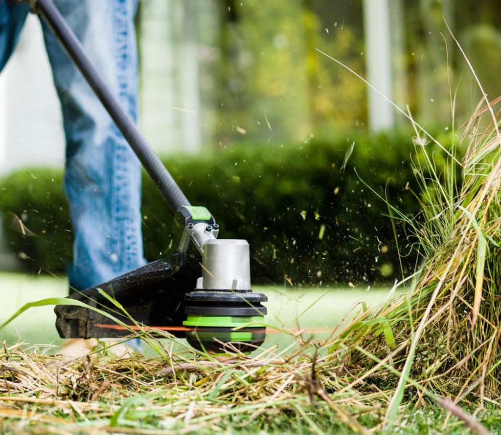 black and green trimmer tool cutting grass