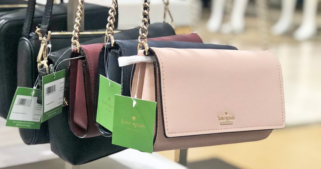 multiple colors of kate spade crossbody bags hanging on store display with green sale tags