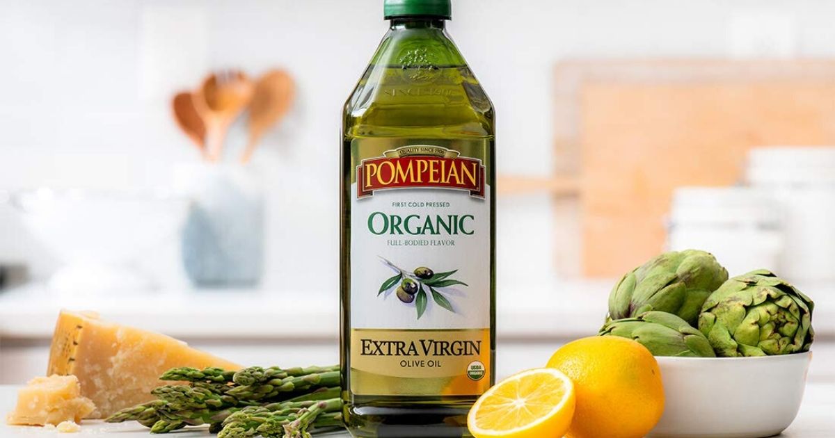 bottle of olive oil with lemons and asparagus on counter in kitchen