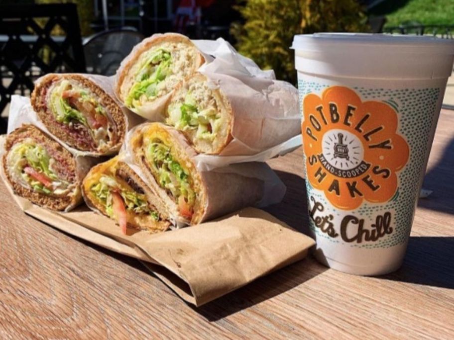 Potbelly Sandwiches in a pile next to drink on table