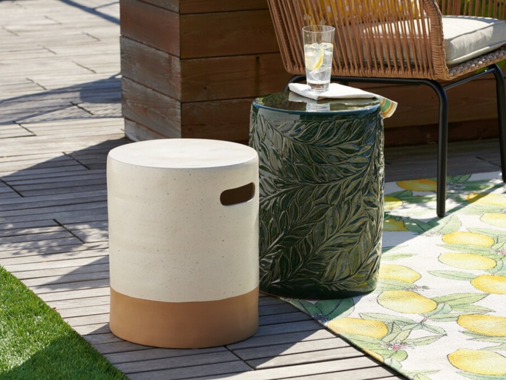 white and tan ceramic drum table and green leaf drum table outside