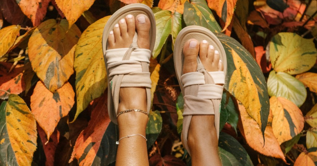 women's tan sandals on feet in air in front of foliage