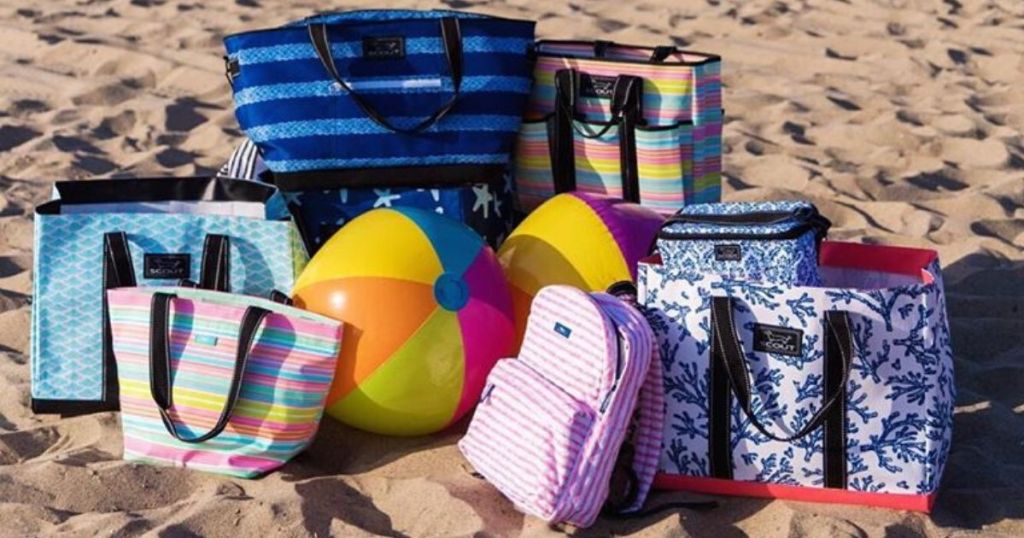 a bunch of tote bags on the beach with a beach ball