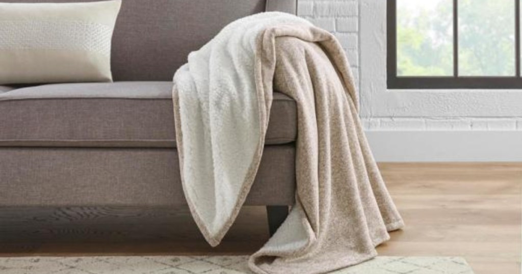 Khaki colored StyleWell Oversized Sweater Knit Sherpa Blanket drapped over couch in living room