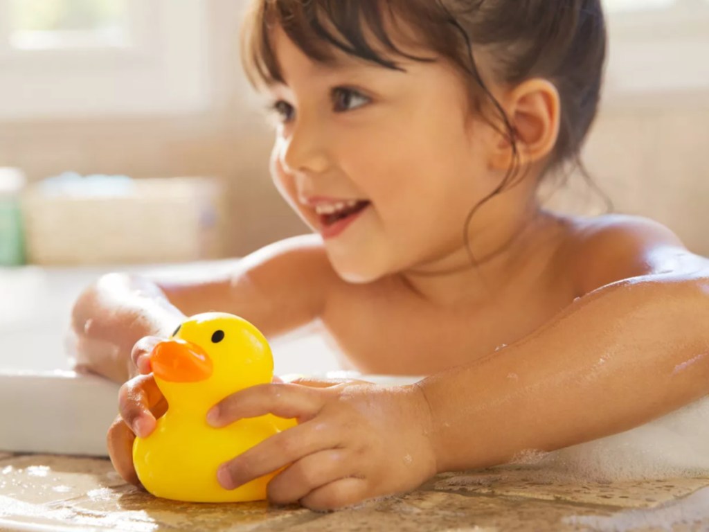 little girl taking a bath and holding a yellow rubber ducky