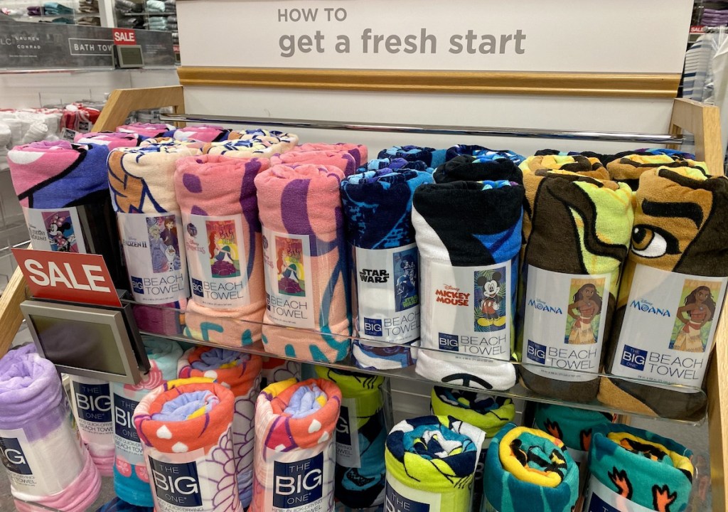 store display rack full of rolled up disney beach towels