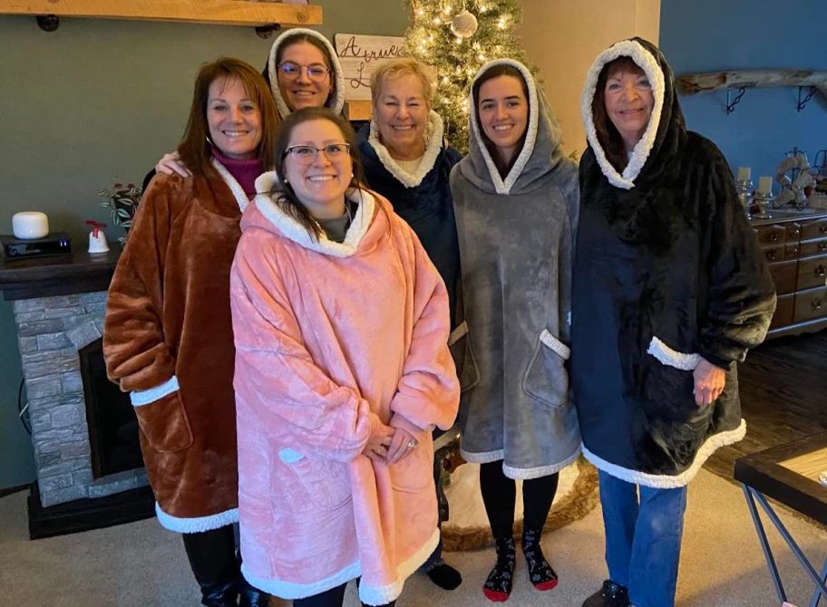 group of women standing together wearing blanket hoodies