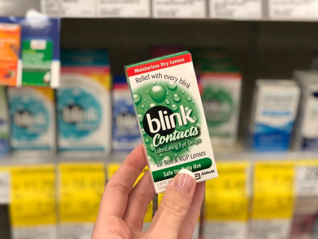 hand holding blink-contacts eye drops in front of sale signs at walgreens