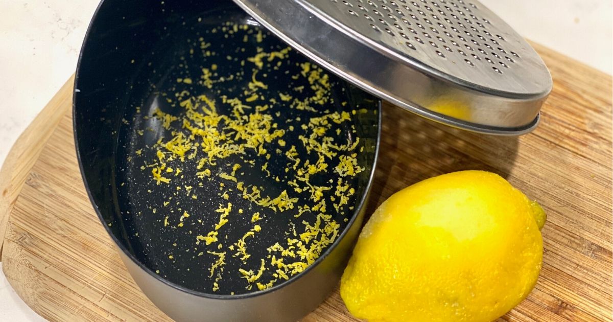 Lemon zest in cheese grater storage onlinepartment next to a lemon