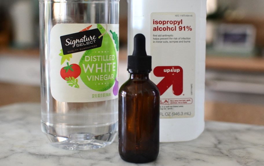 bottles of vinegar rubbing alcohol and dropper bottle on countertop