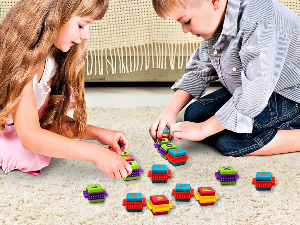 kids playing with Picasso Tiles 52-Piece Alphabet Bristle Block Building Set