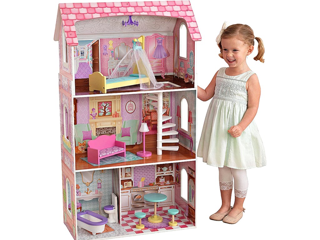 little girl standing next to KidKraft Penelope Dollhouse