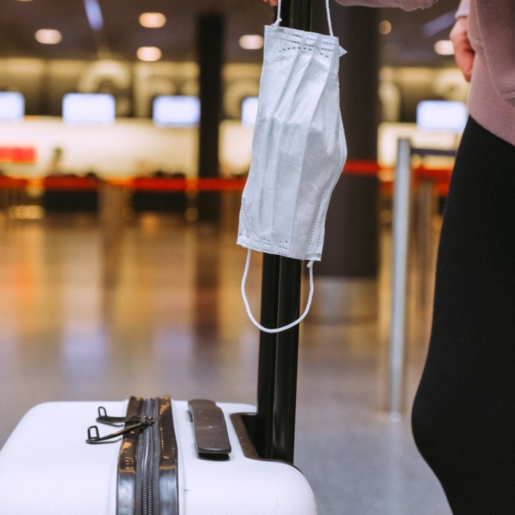 mask hanging on luggage at airport