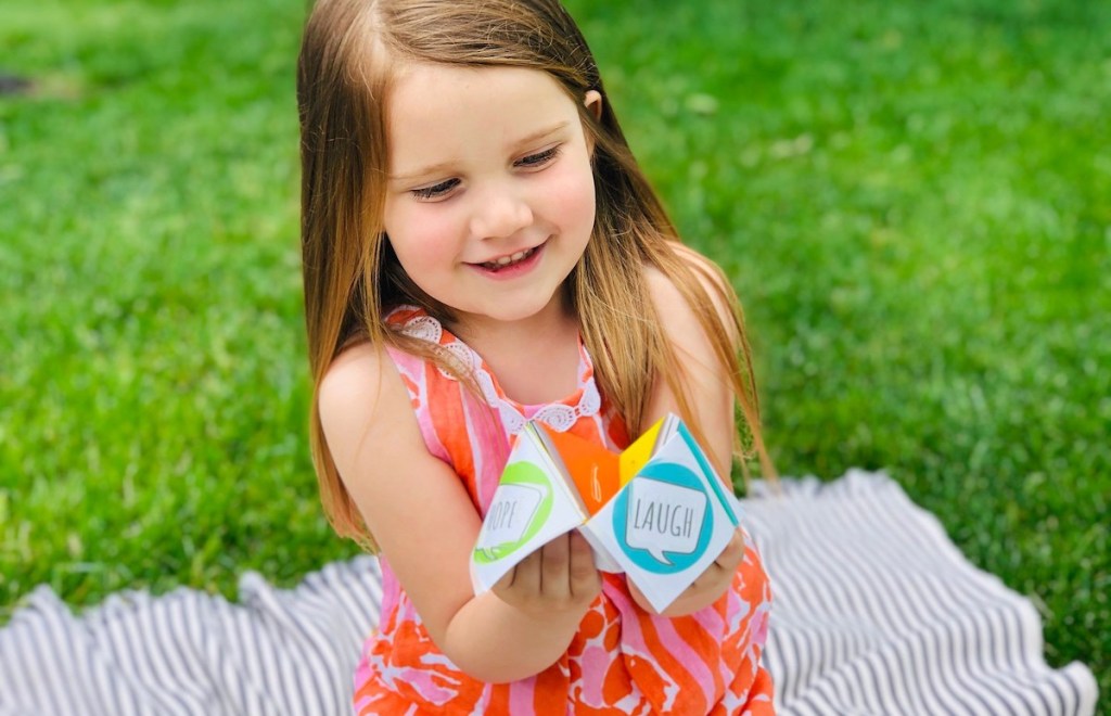 girl holding colorful paper toy in hands smiling