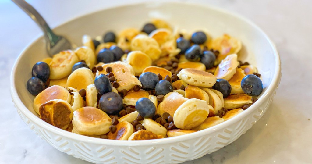 White bowl with mini pancakes blueberries and chocolate chips inside