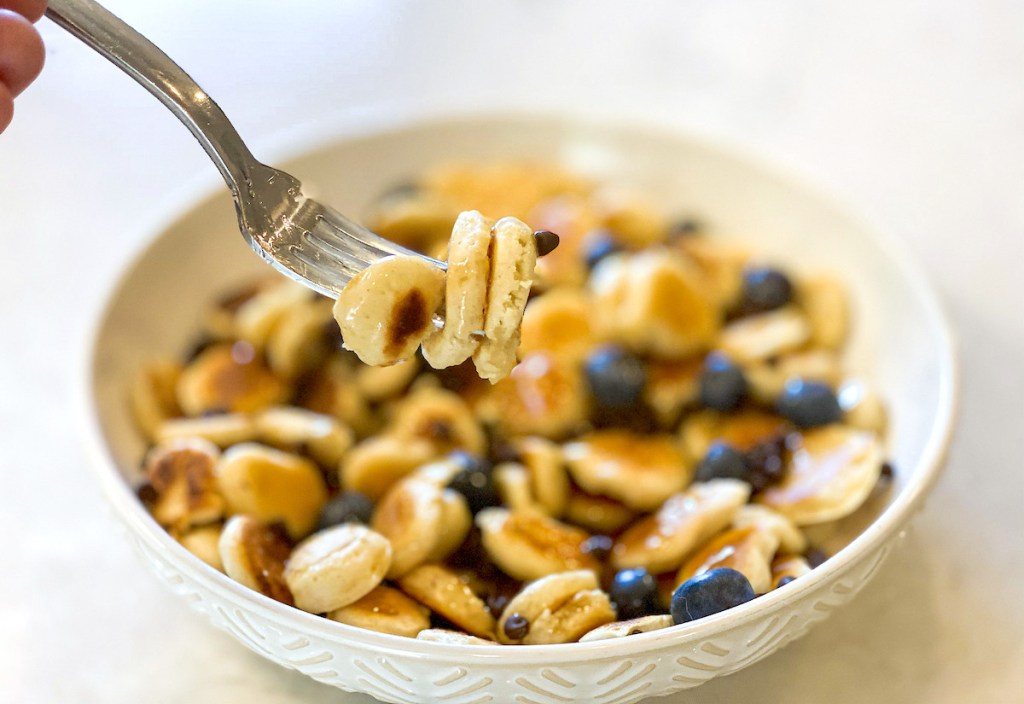 White bowl filled with mini pancakes and blueberries