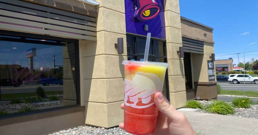 hand holding a slushy drink in front of restaurant